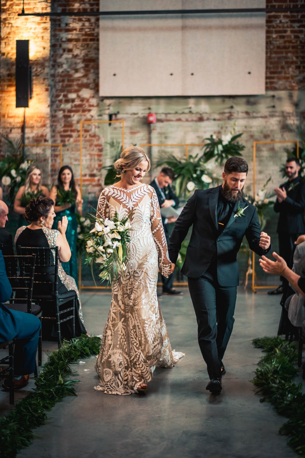 bride and groom walking the recessional as groom fist bumps one of the guests