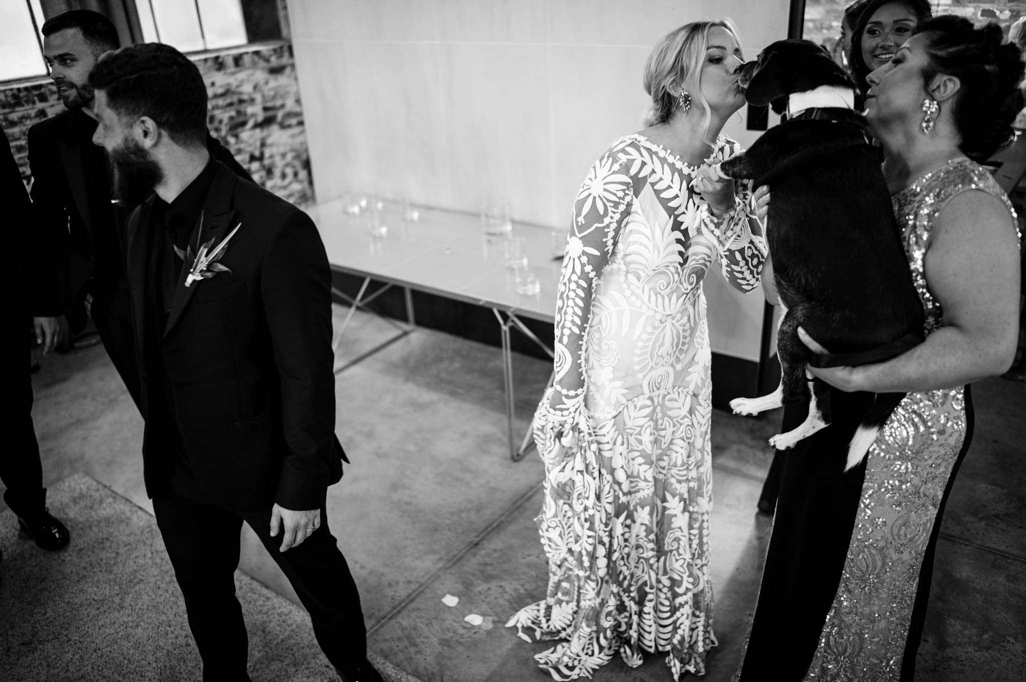 bride and mother of the bride kiss their dog after the wedding ceremony