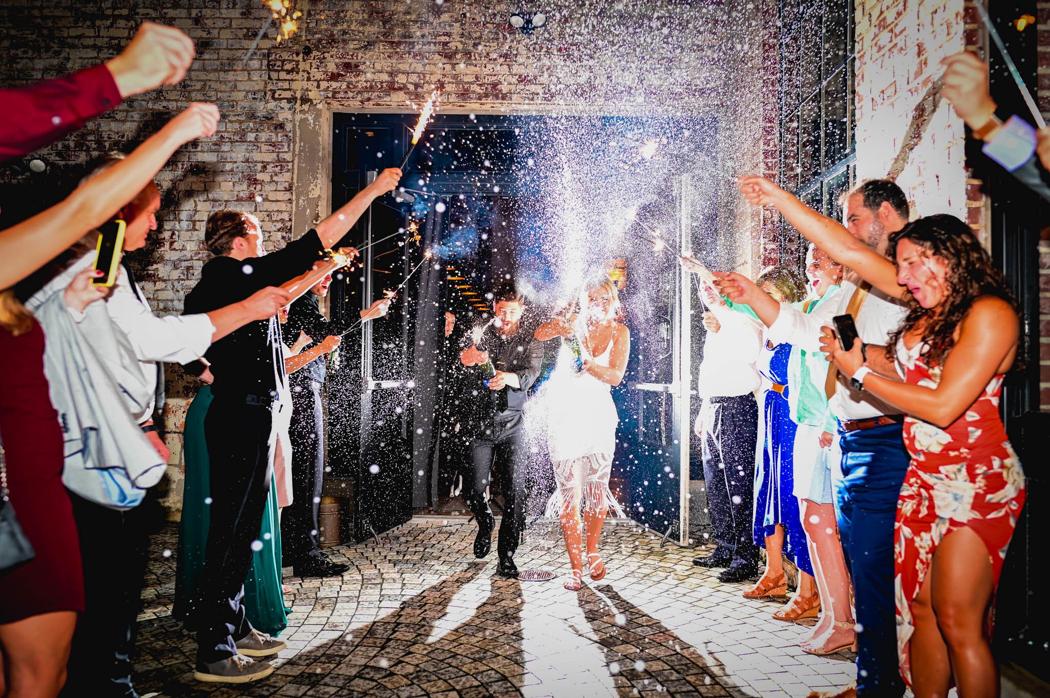 bride and groom exit their wedding with champagne and sparklers blasting into the air