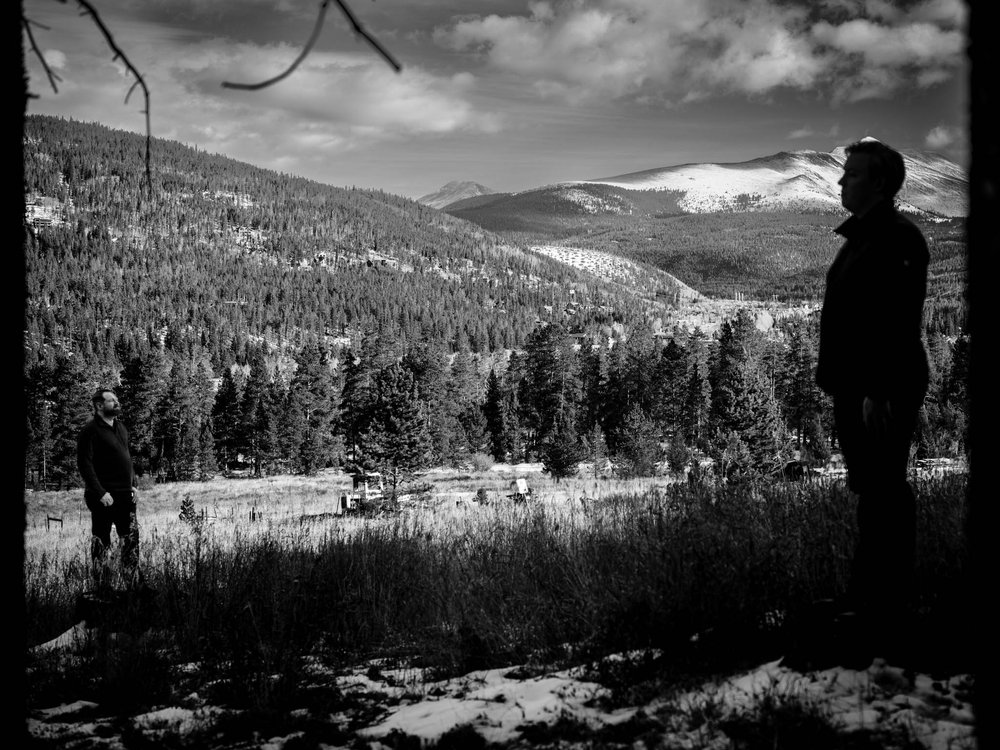 couple stand on the edge of the forest with breckenridge behind them