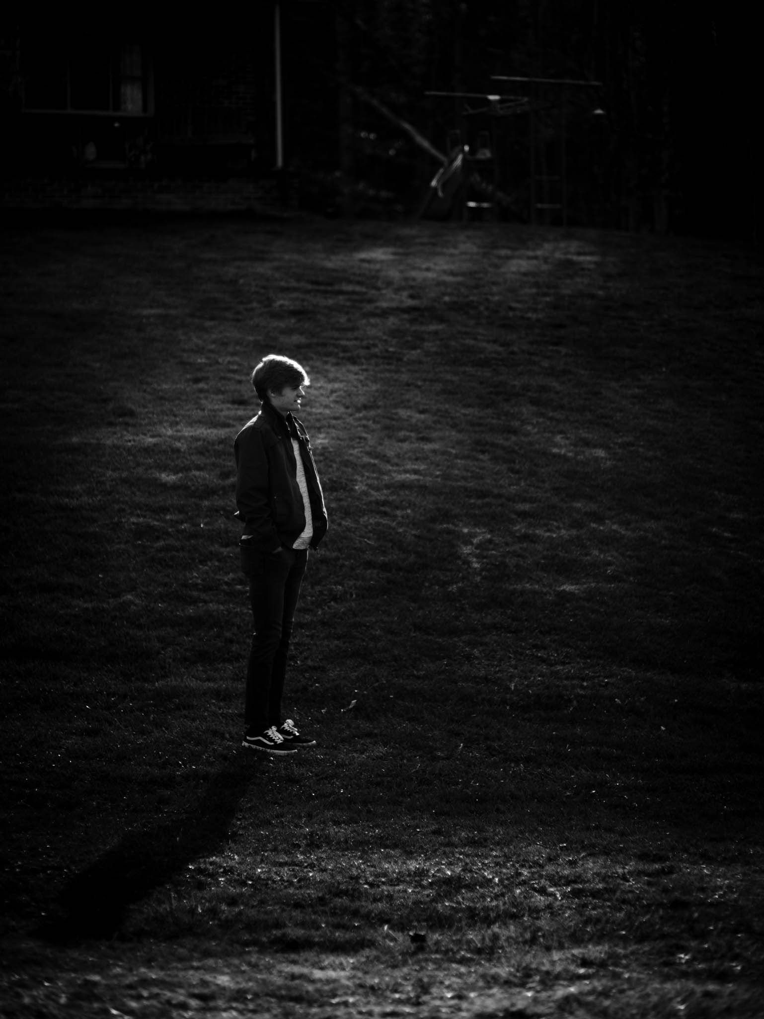 boy standing in the sunlight and shadows in the backyard during a game