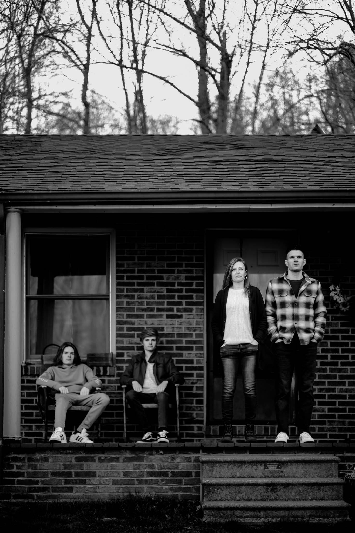 family poses stoically on the front porch of their grandparents house