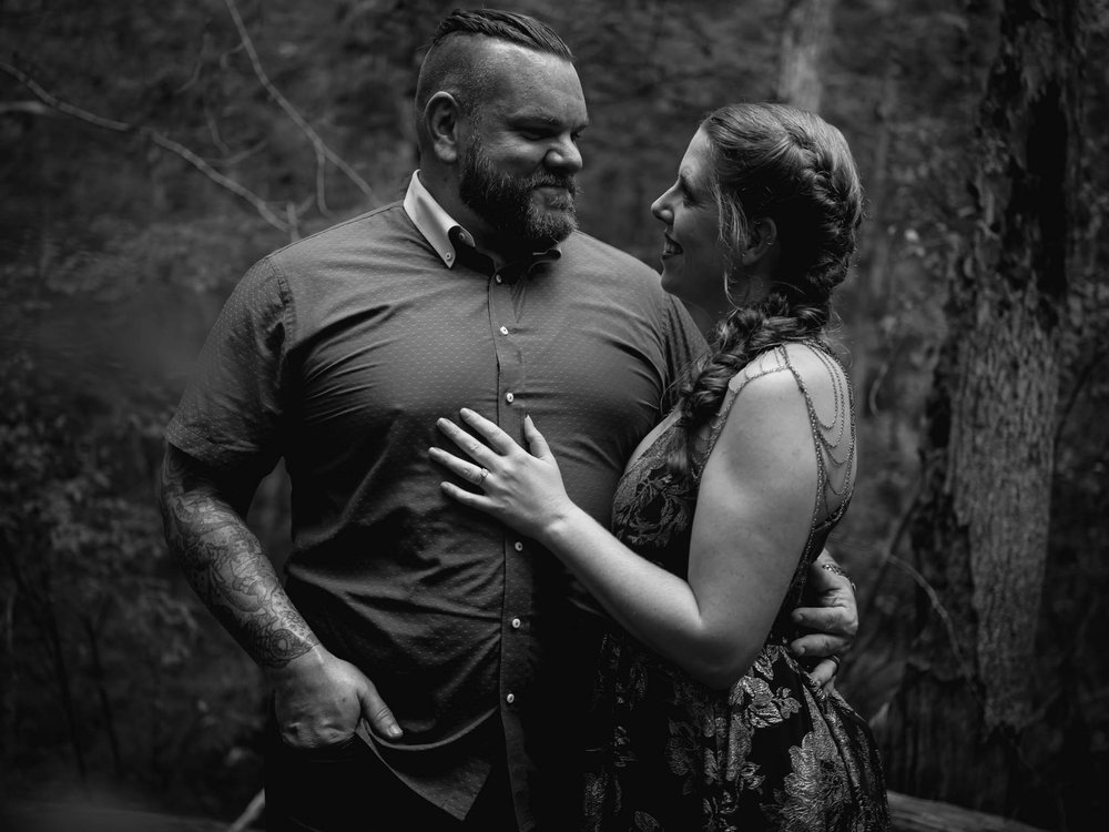 couple stand together in a forest 