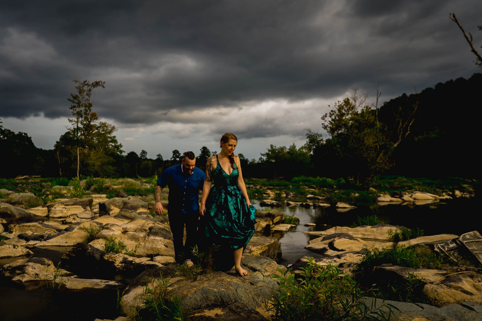 couple walking on boulders near river