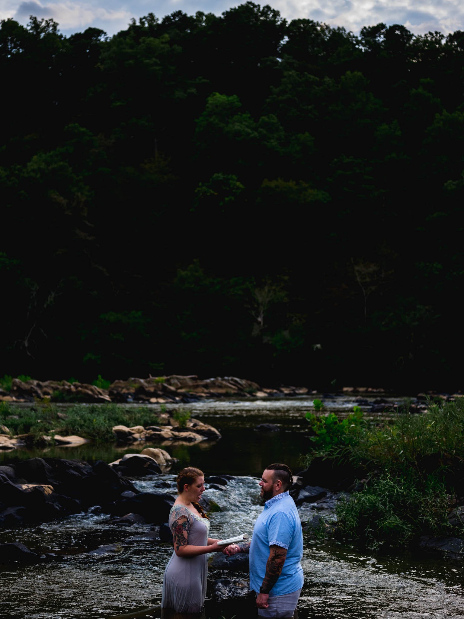 bride reads vow renewal while standing in a river pool