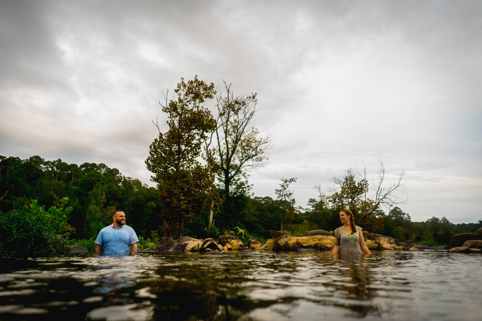 couple standing apart while deep in a river