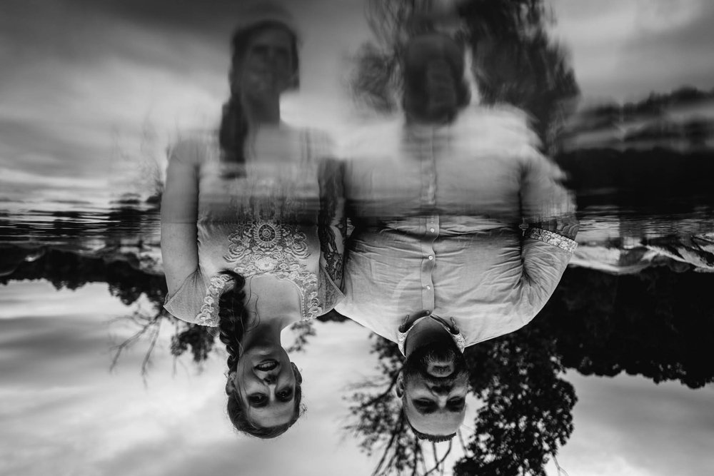 an upside down image of the reflected ripples of the couple in the water