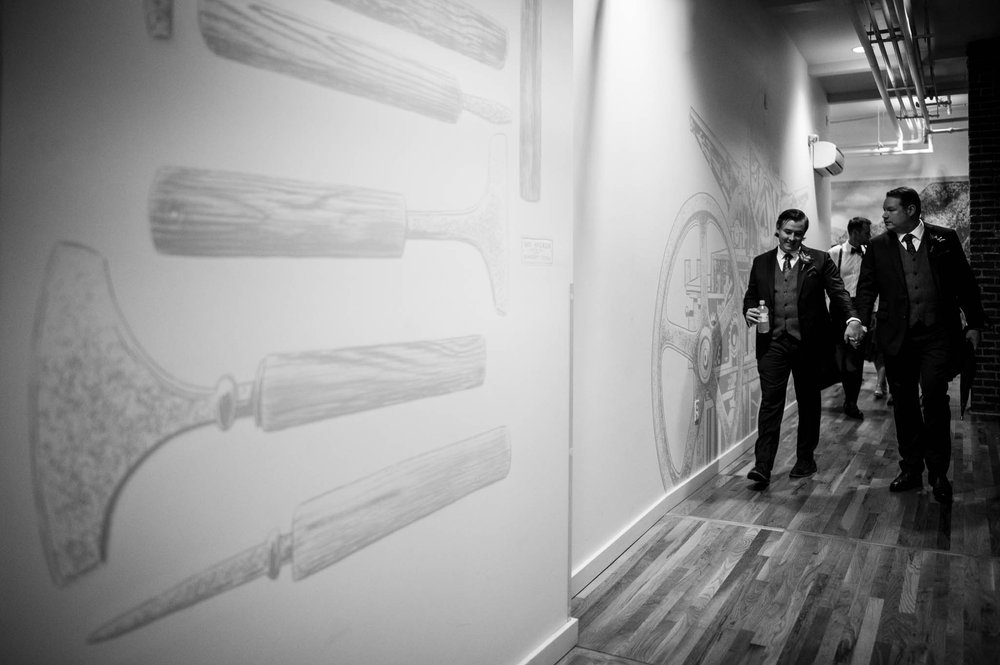 two grooms walk together down a hallway