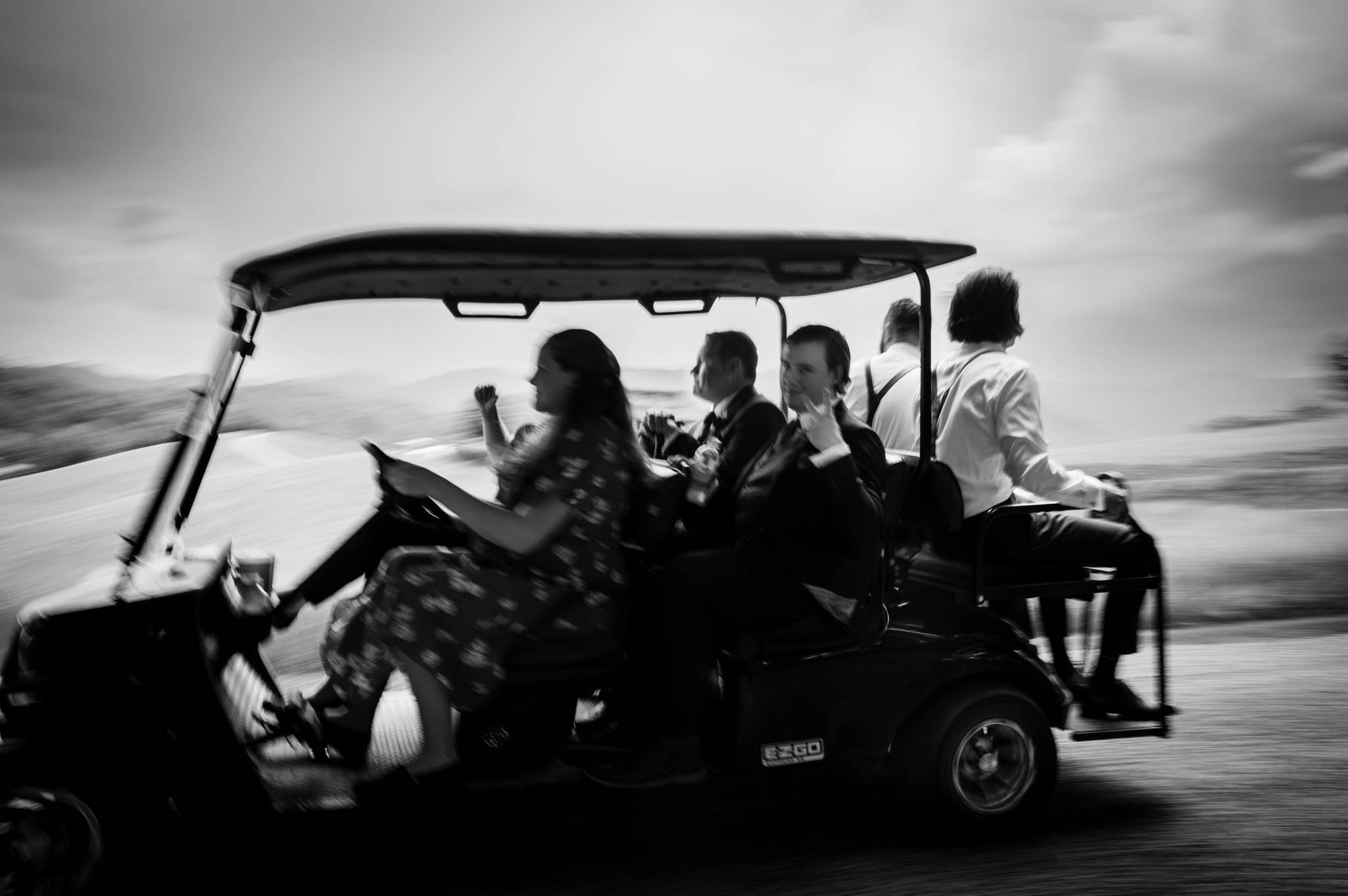 the two grooms and wedding party are whisked off to the wedding ceremony on a golf cart