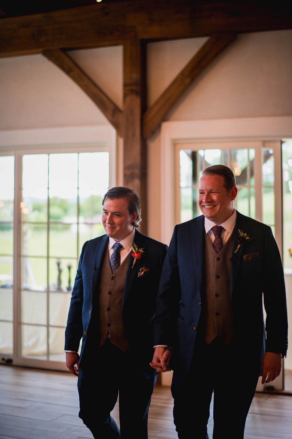 two grooms walk in smiling for their wedding ceremony