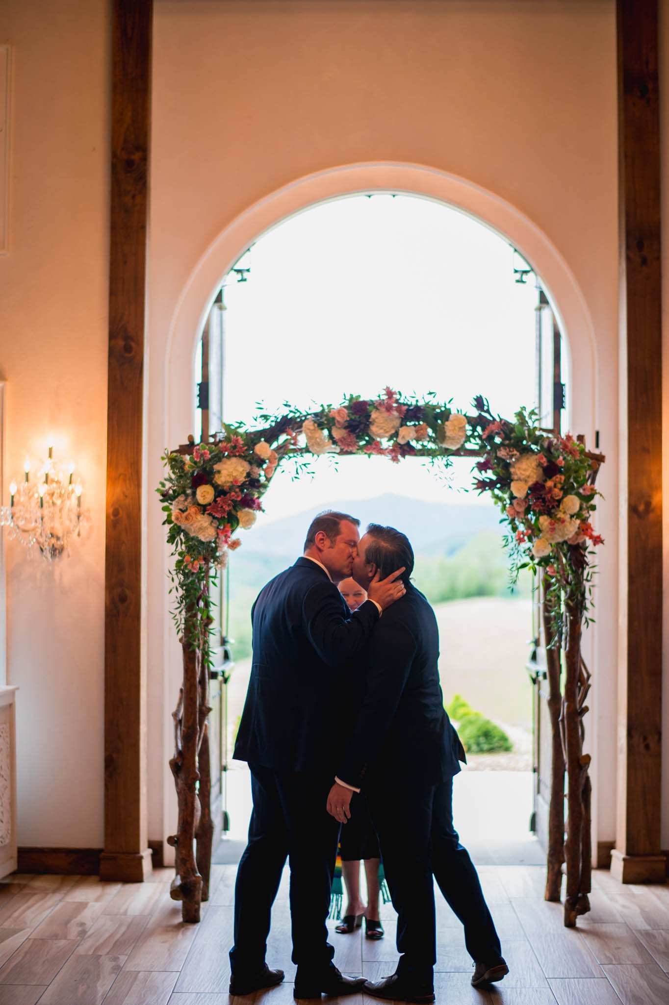 two grooms kiss at the end of their wedding ceremony