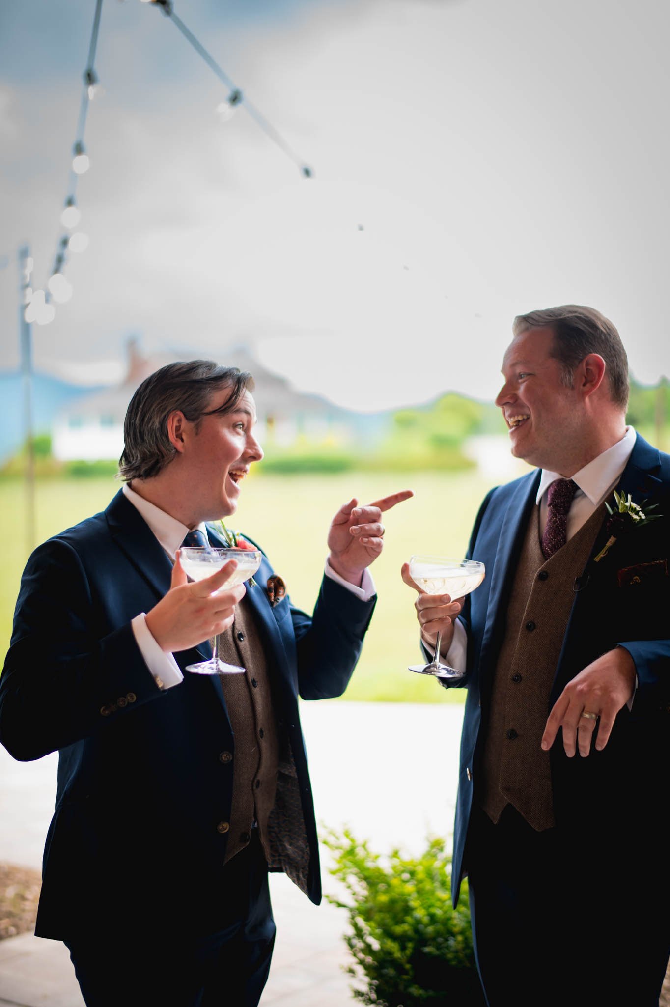 two grooms enjoy a drink and a chat after their wedding ceremony