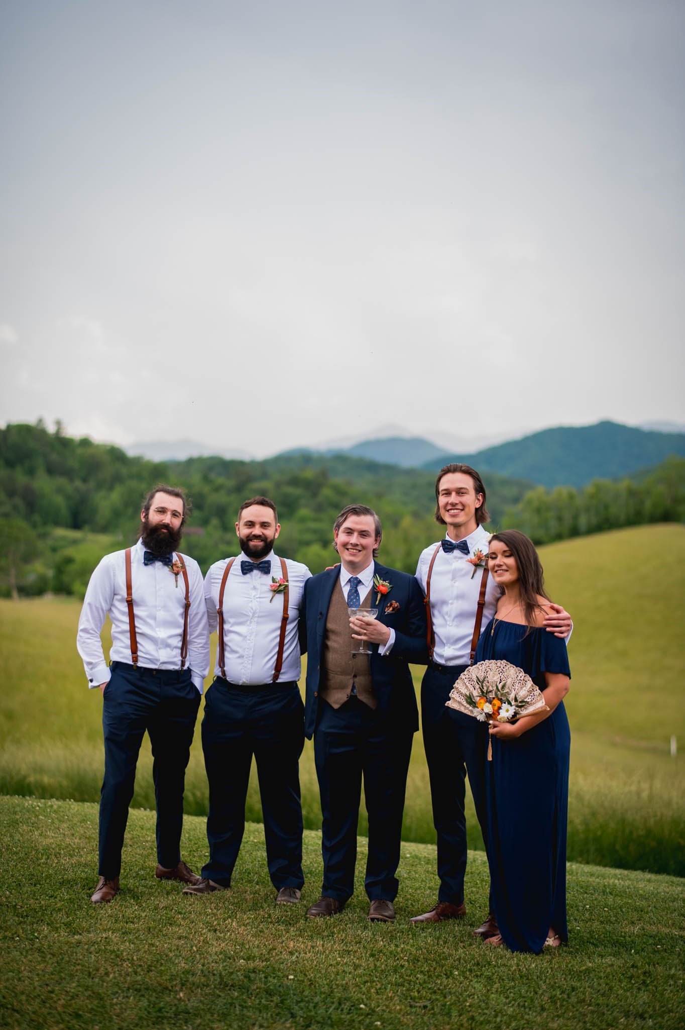a grooms and his wedding party stand with the blue ridge mountains behind them