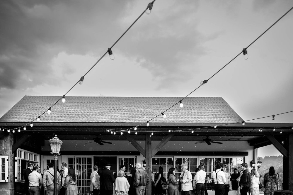 wedding guests enjoy cocktails and conversation as the rain begins to fall