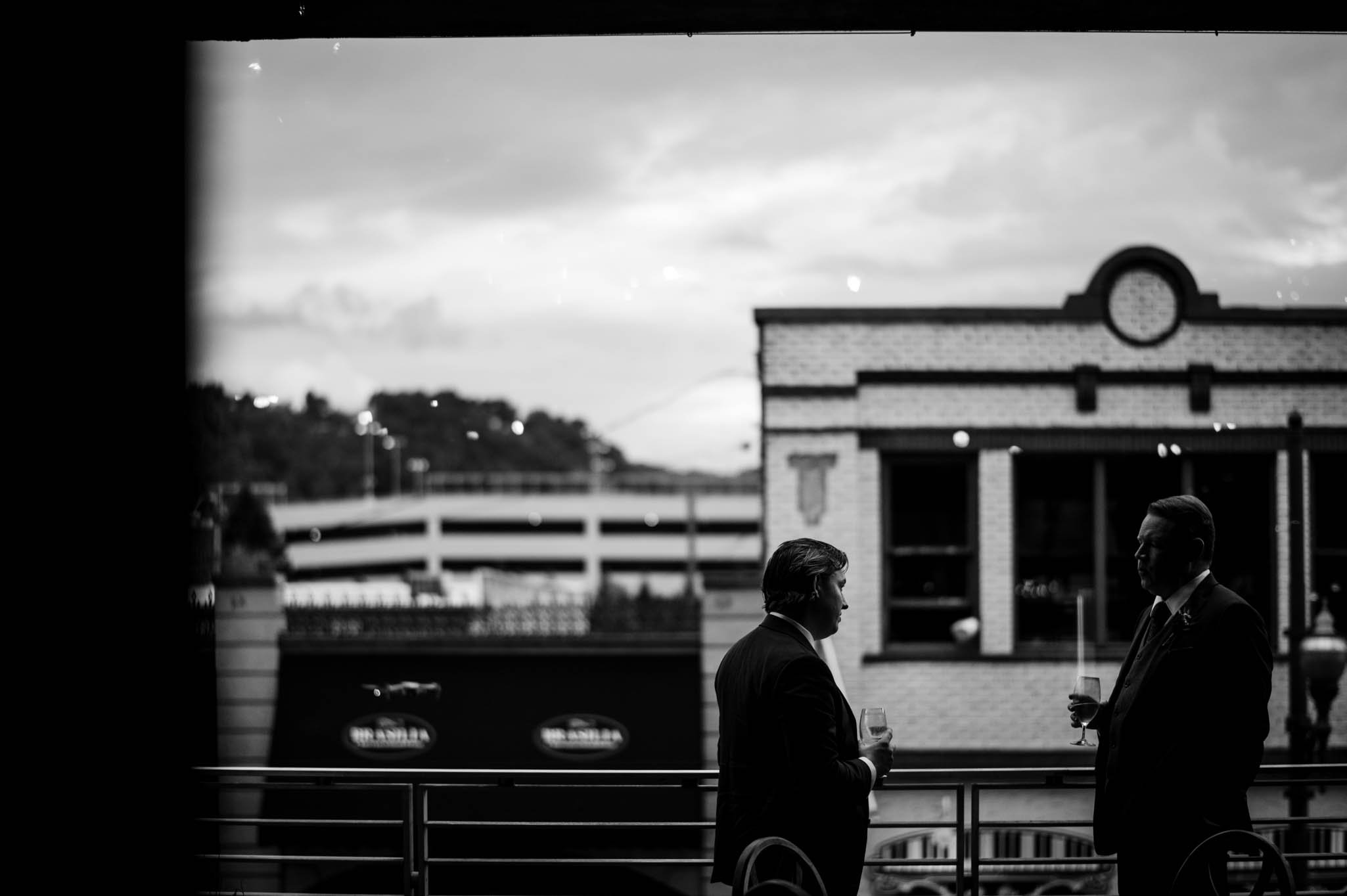 two grooms share a quiet moment on the balcony at the venue in asheville