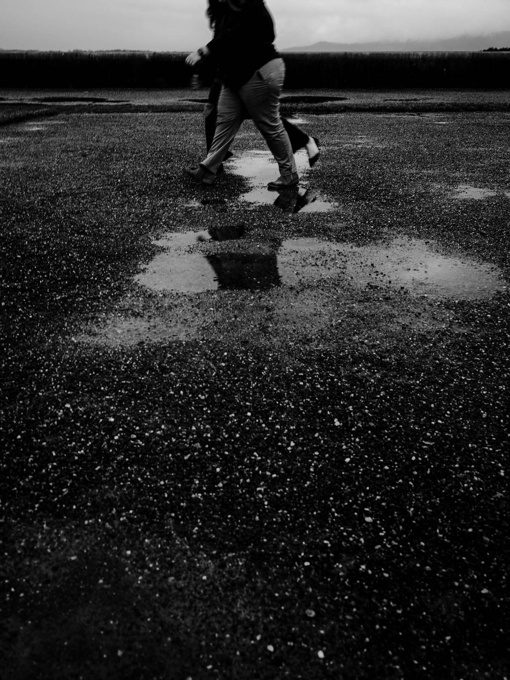 couple jumps over puddle