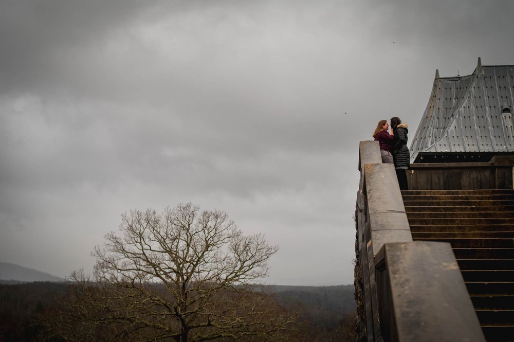 couple stands at the top of a set of stairs with the mountain landscape to their backs