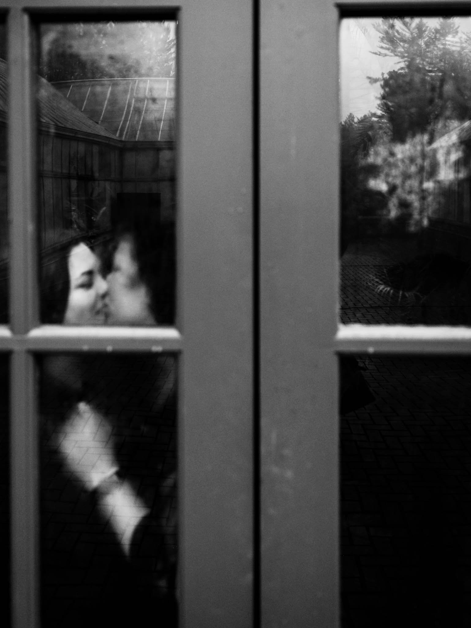 couple kissing in behind foggy doors of Biltmore greenhouse