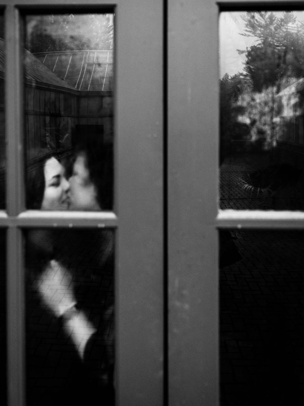 couple kissing in behind foggy doors of Biltmore greenhouse