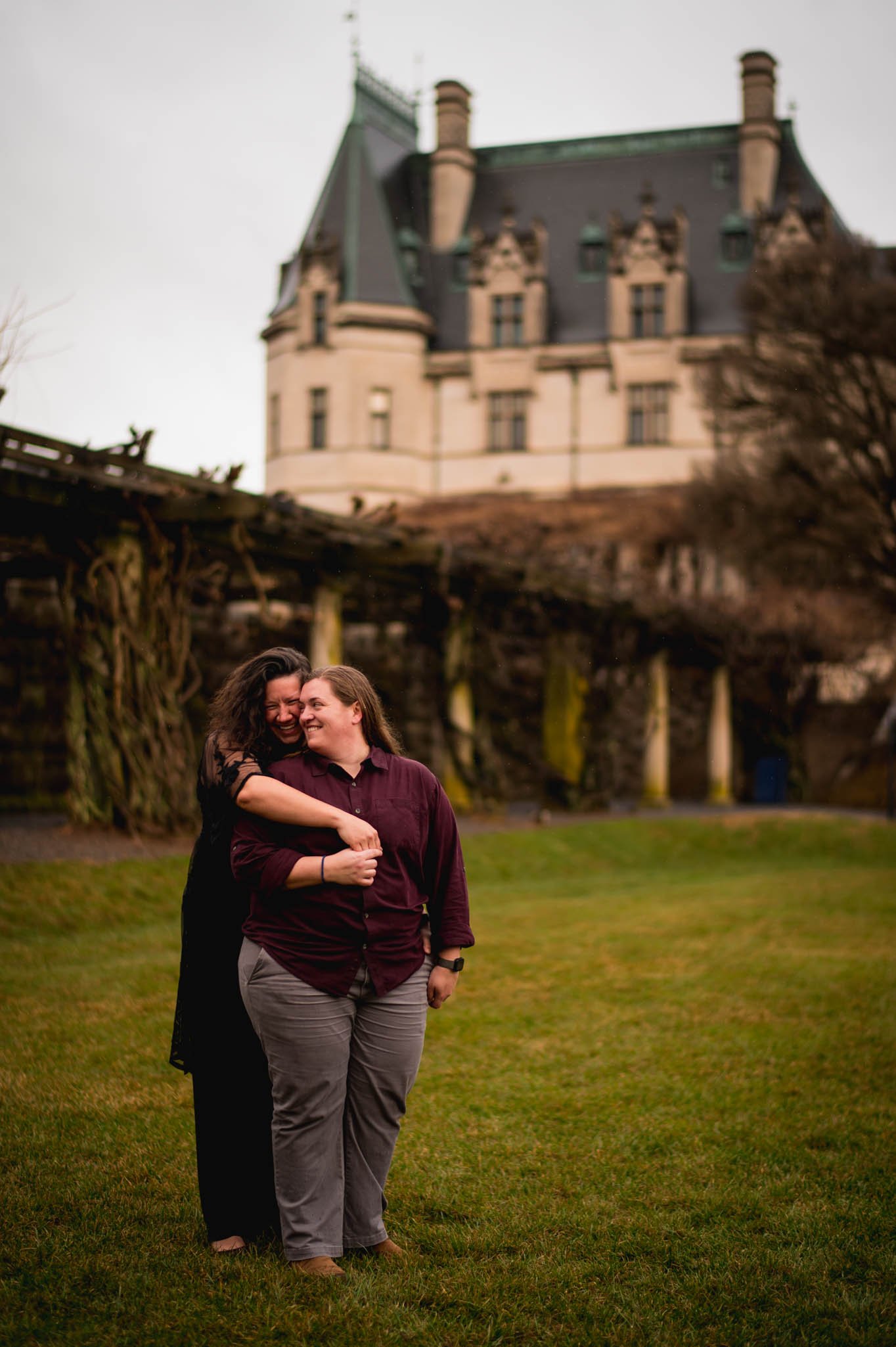 couple embracing on the lawn in front of the Biltmore house