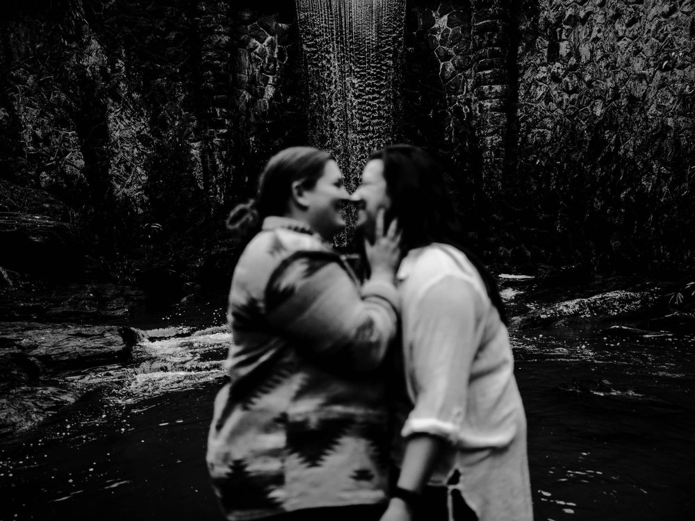a kissing couple is blurred out in front of the Biltmore waterfall