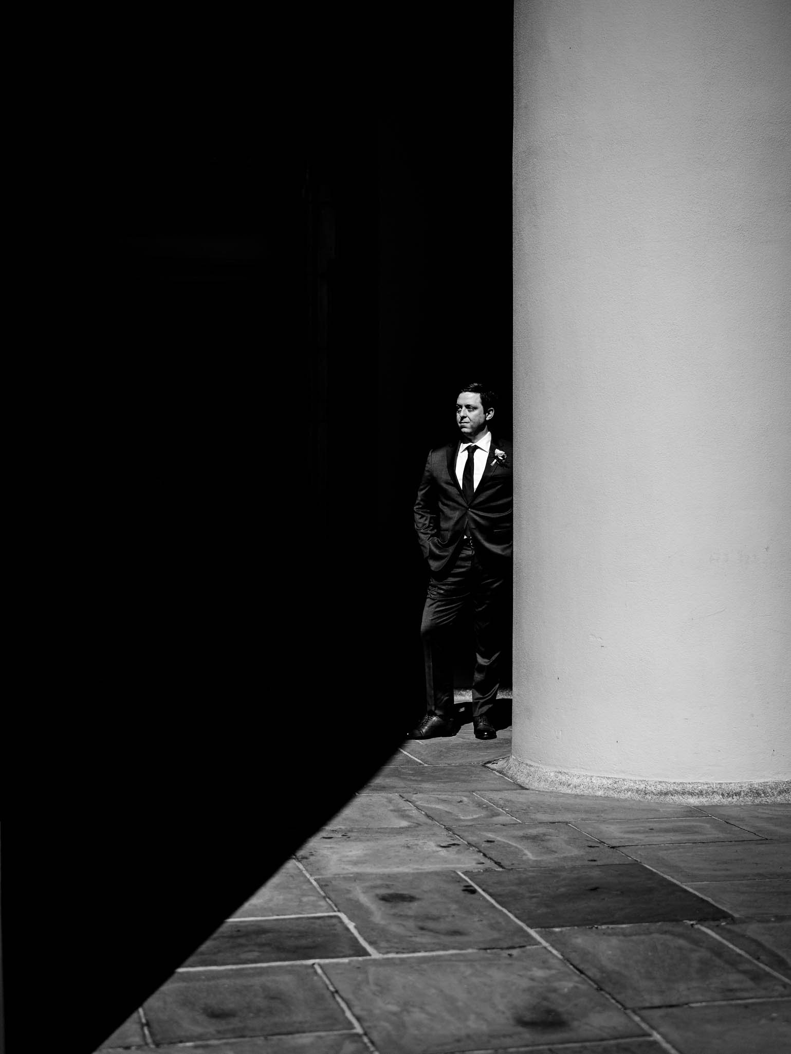 groom standing in the shadow of the columns at Wait Chapel