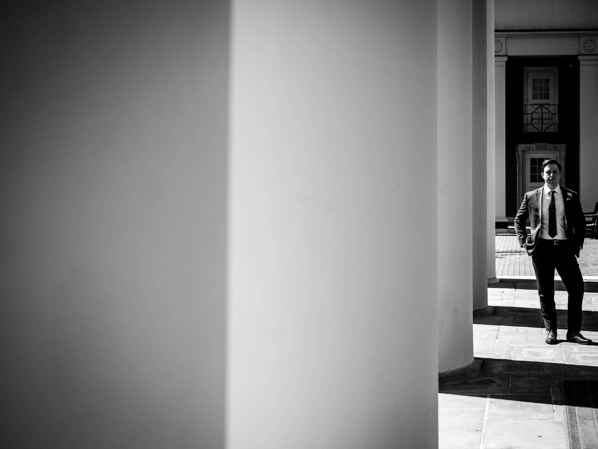 groom standing with the columns outside of Wait Chapel