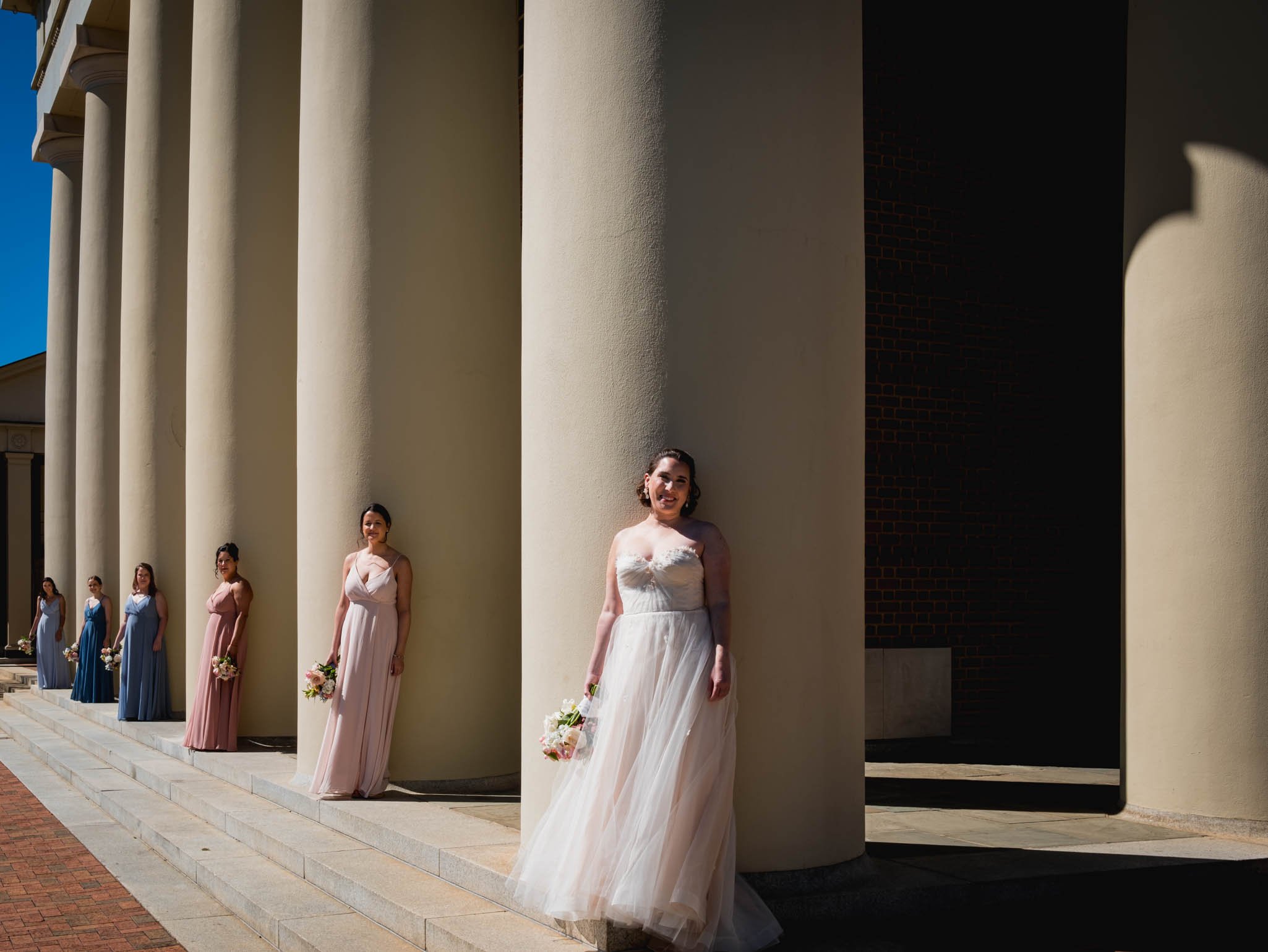 bride and bridesmaids stand in front of the columns outside Wait Chapel