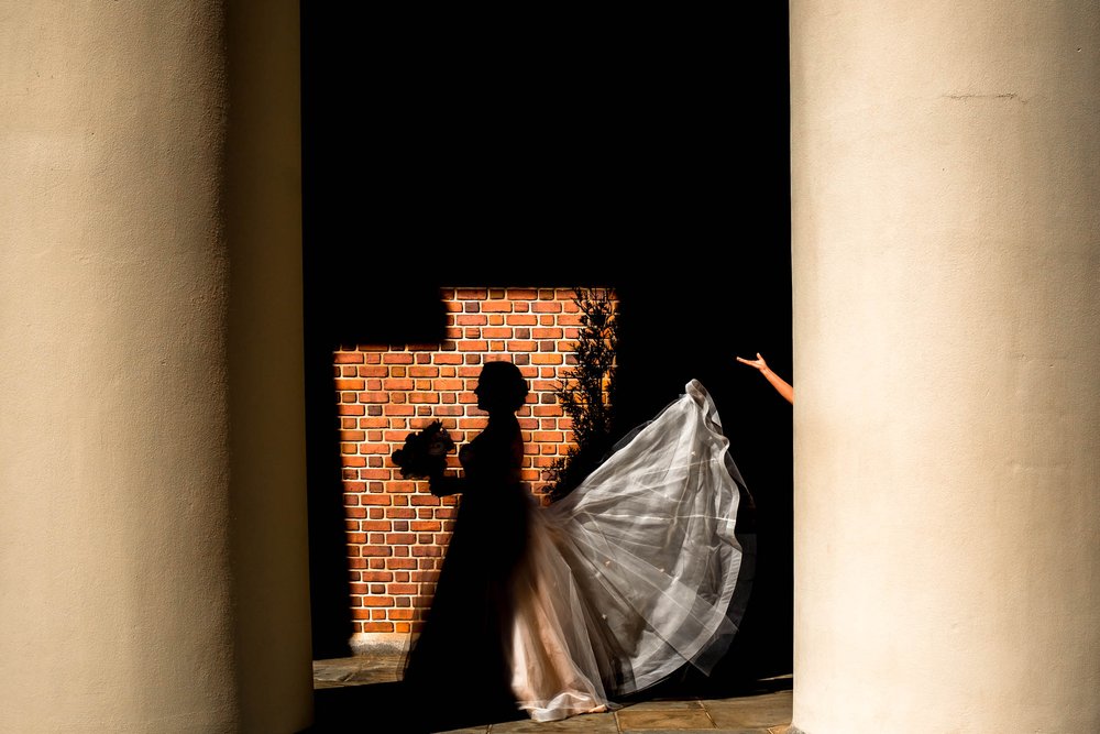 brides train is fluffed in the sunlight outside Wait Chapel