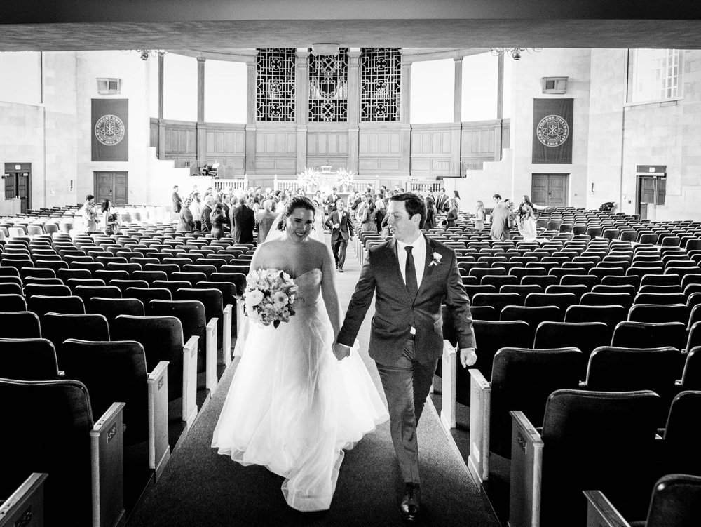 bride and groom smile with one another during the recessional at Wait Chapel