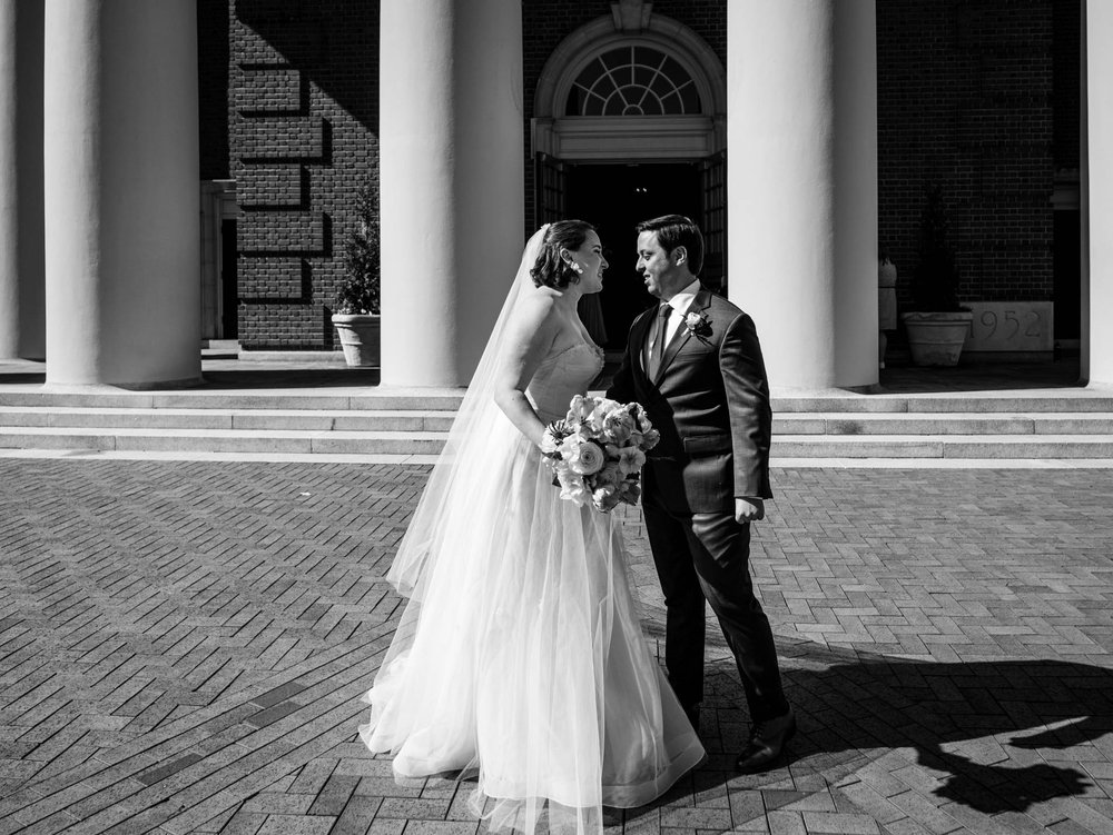 bride and groom smiling as they stand outside Wait Chapel after their wedding