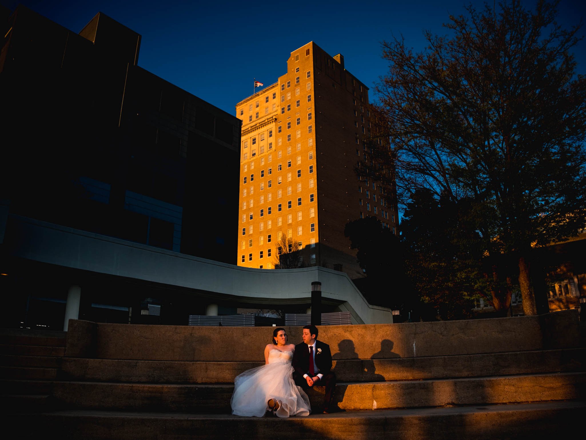 bride and groom sit in the light of the sunset outside Milton Rhodes Center for the Arts