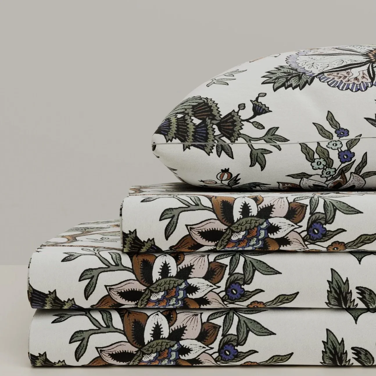 Une pile de trois livres empilés avec des couvertures à motifs floraux, la partie supérieure est un coussin décoratif à motifs floraux.
