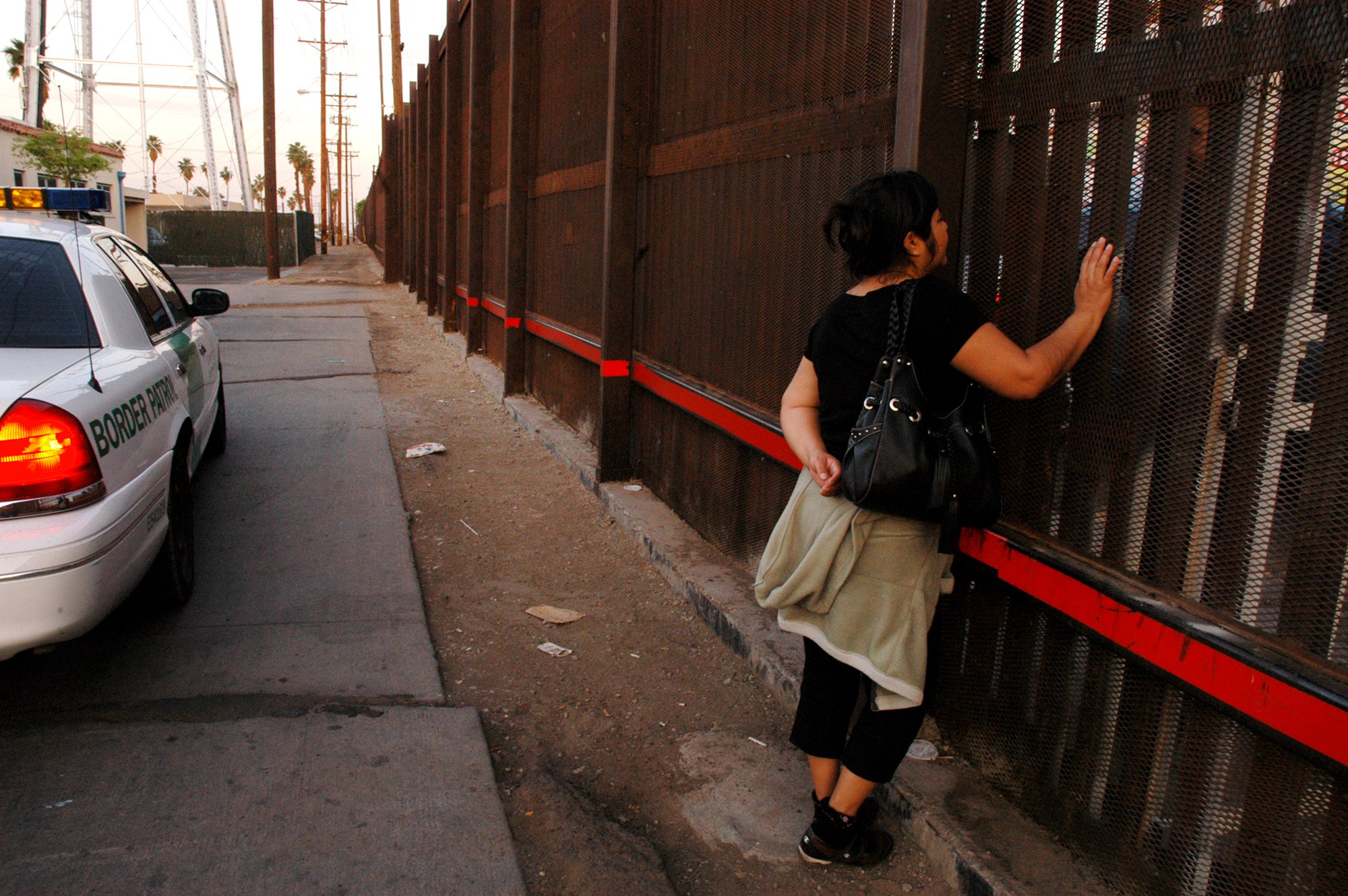   &nbsp;A woman (on the California side of the fence) meets her husband (on the Mexico side of the fence) to talk. She works in California, and does so legally, but while her permit and documents are being renewed she stays in the U.S. rather than re