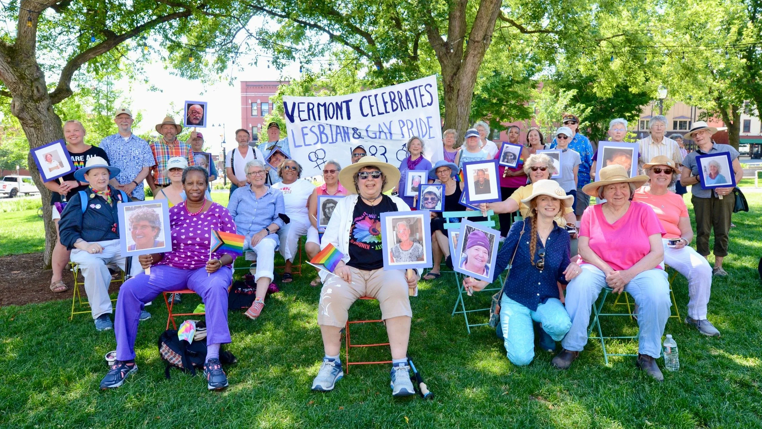 A group of people seated outside in front of a banner reading "Vermont Celebrates Lesbian & Gay Pride 1983"