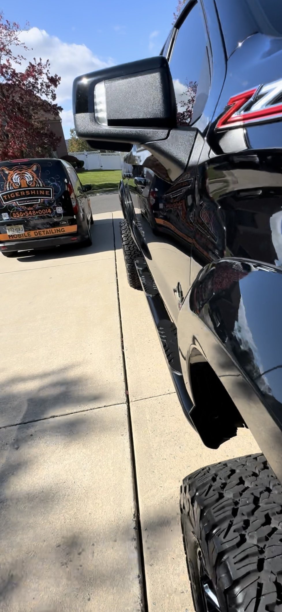Black pickup truck with a mirror finish, the Tigershine van behind it