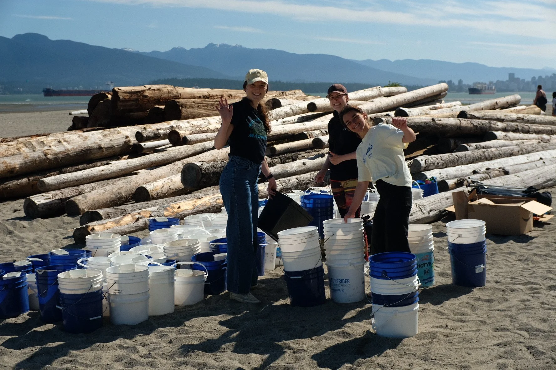 People standing with buckets on a beach