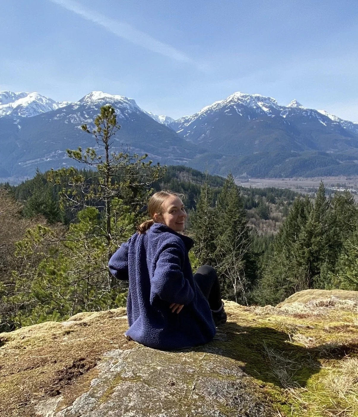 Hayley sitting on a rock in the mountains