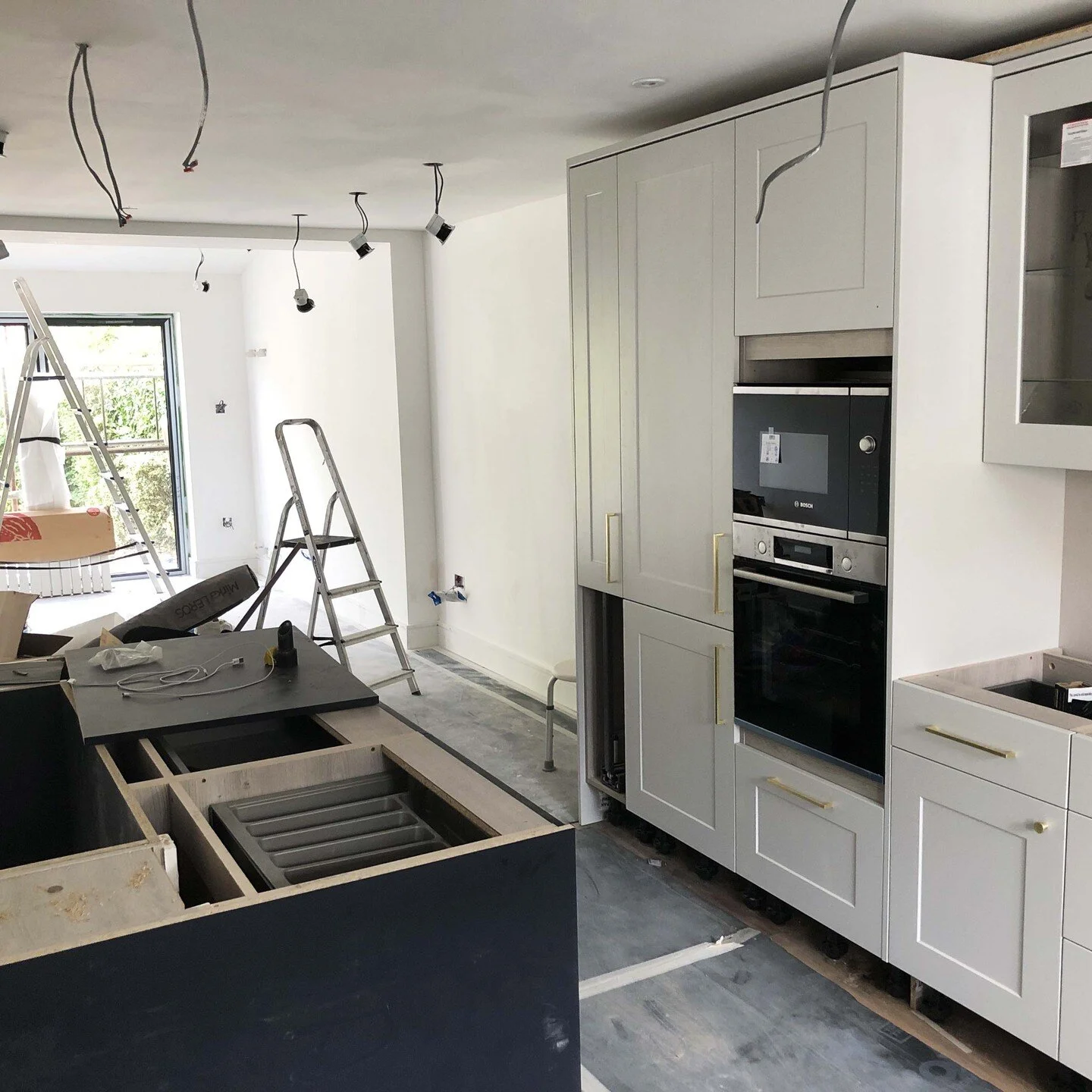 Kitchen installation day. Shaker style cabinets in dove grey with navy island and brass ironmongery.

#kitchendesign #refurbishment #howdenskitchen