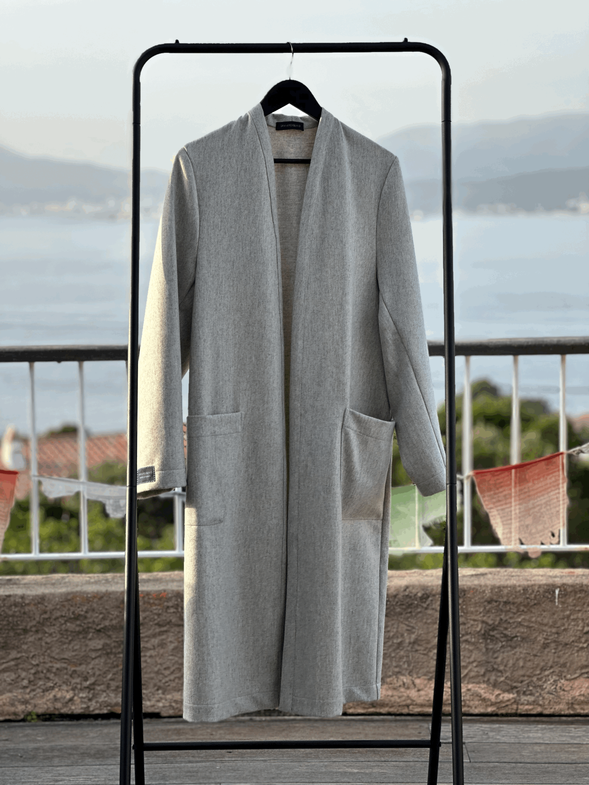 Full-length Granite Island Sparkling Ash grey kimono coat hanging on a rail, showing its open front, relaxed silhouette and two large patch pockets.
