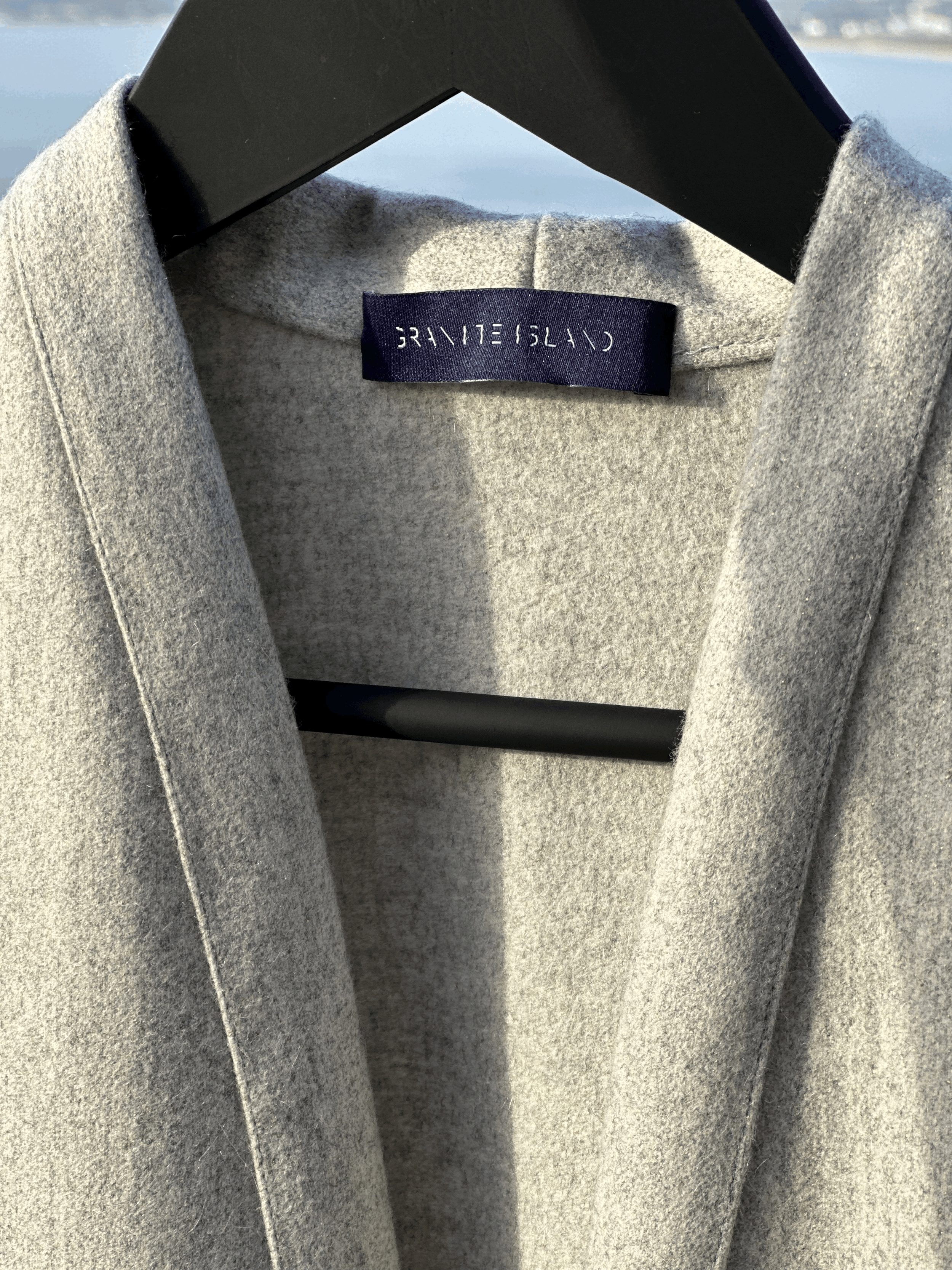 Close-up of the Granite Island Sparkling Ash kimono coat's open collar, textured grey fabric and interior woven brand label.