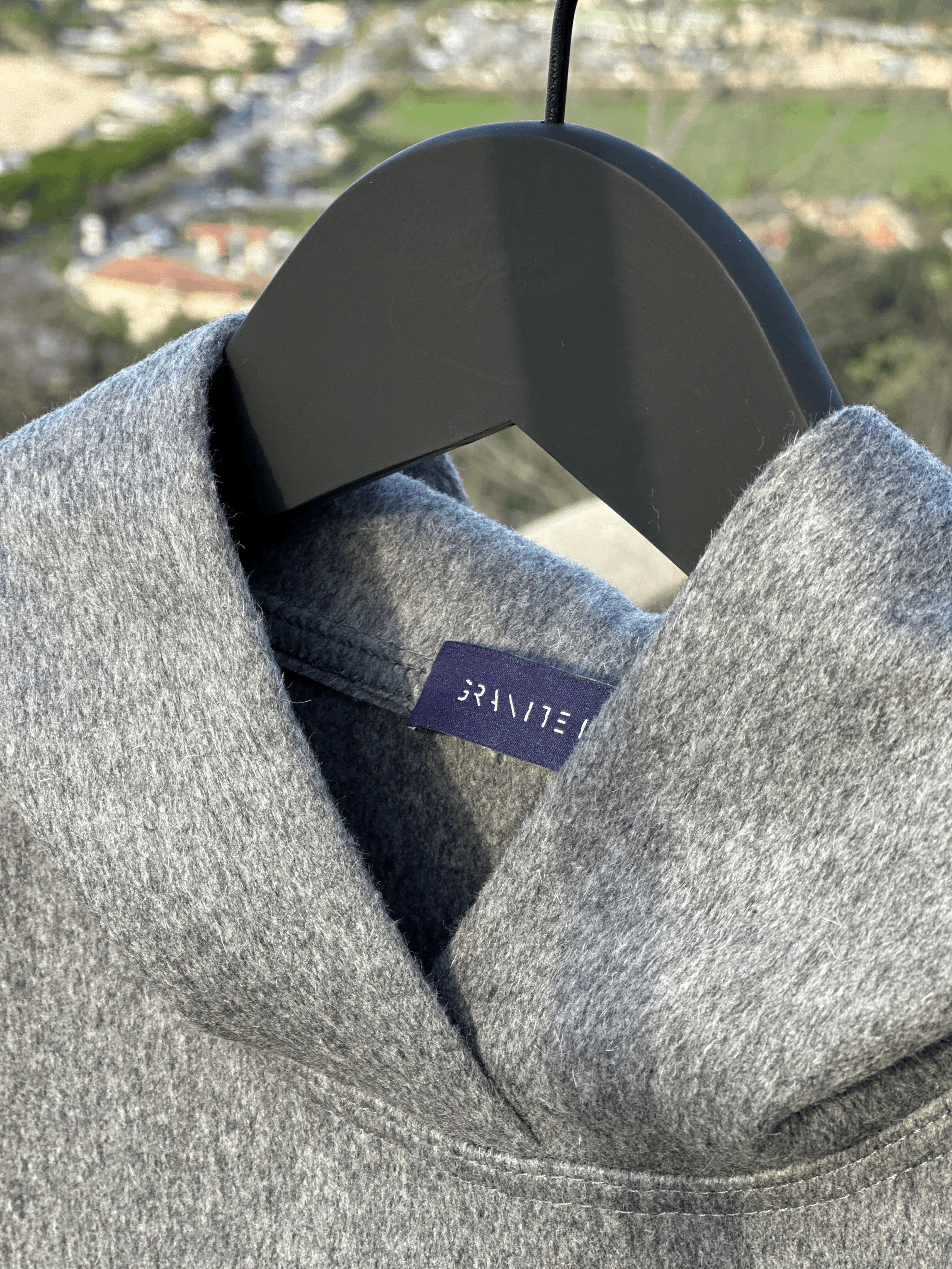 Close-up of the Granite Island Silvery Grey Angora Hoodie on a hanger, showing the neckline, textured fabric and interior woven brand label.