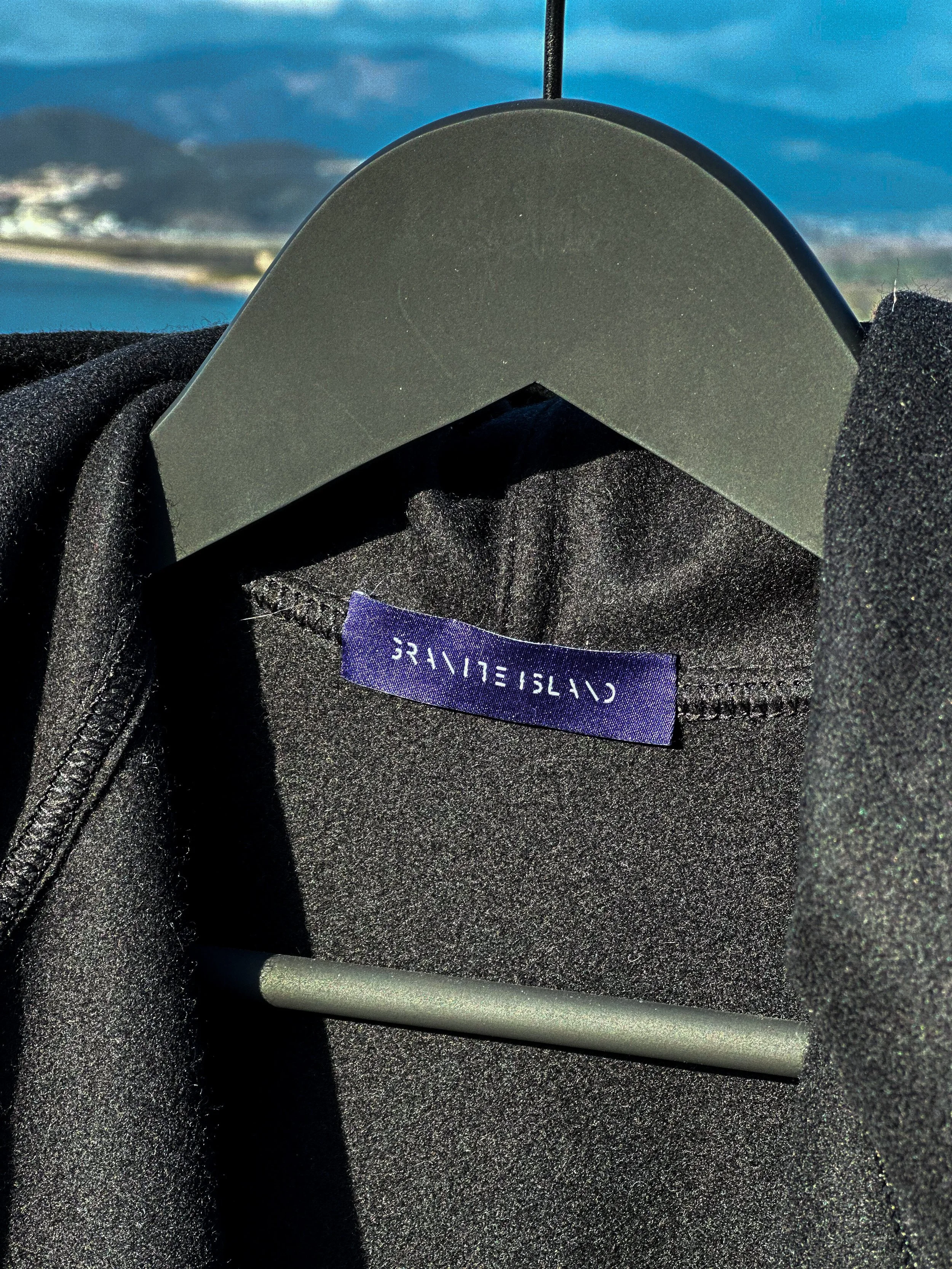 Close-up of the Granite Island woven label inside the black kimono overcoat, showing the dark textured fabric and interior finishing.
