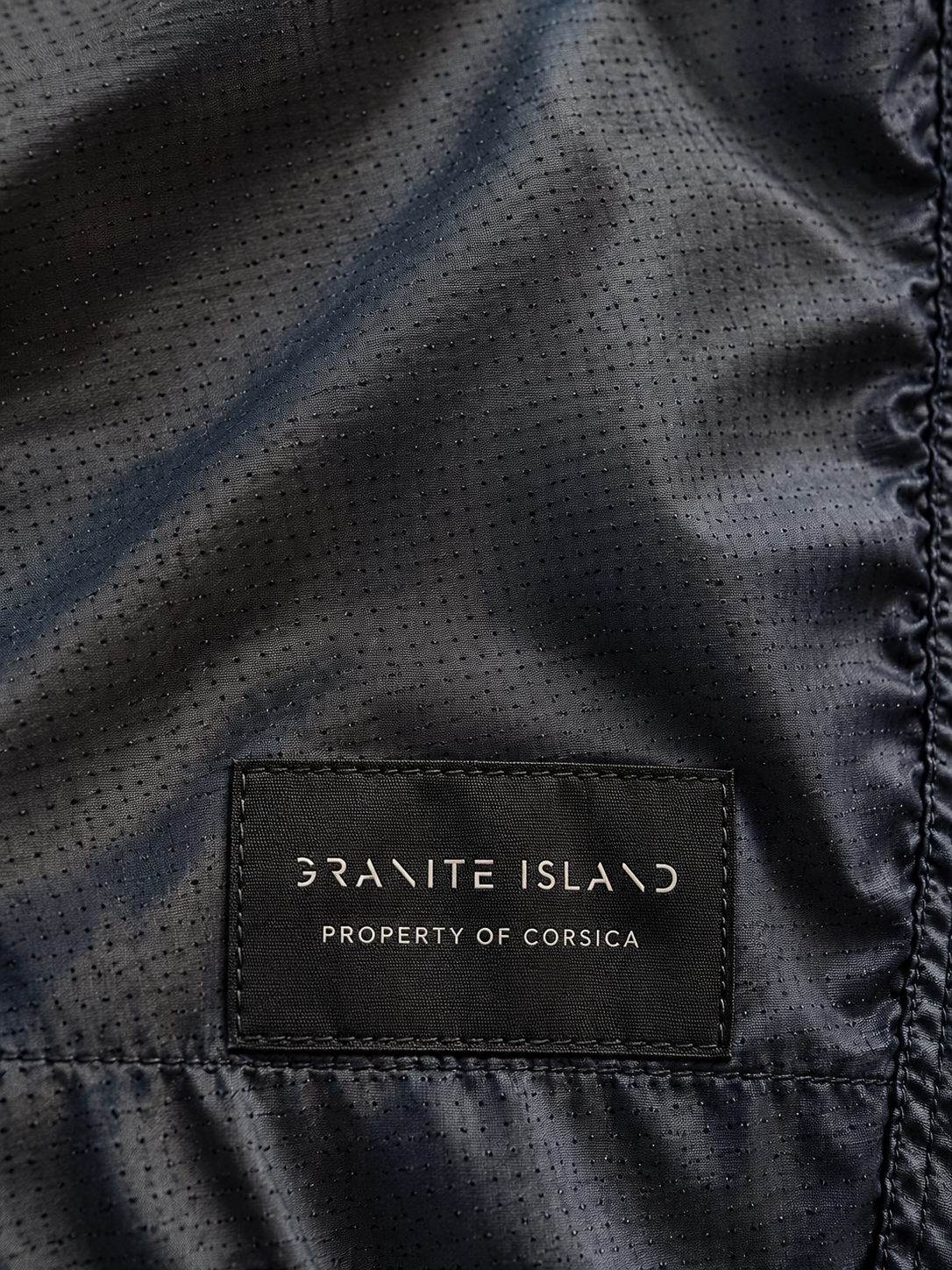Close-up of the Granite Island Property of Corsica label stitched inside the MONTECITO navy blue swim shorts.
