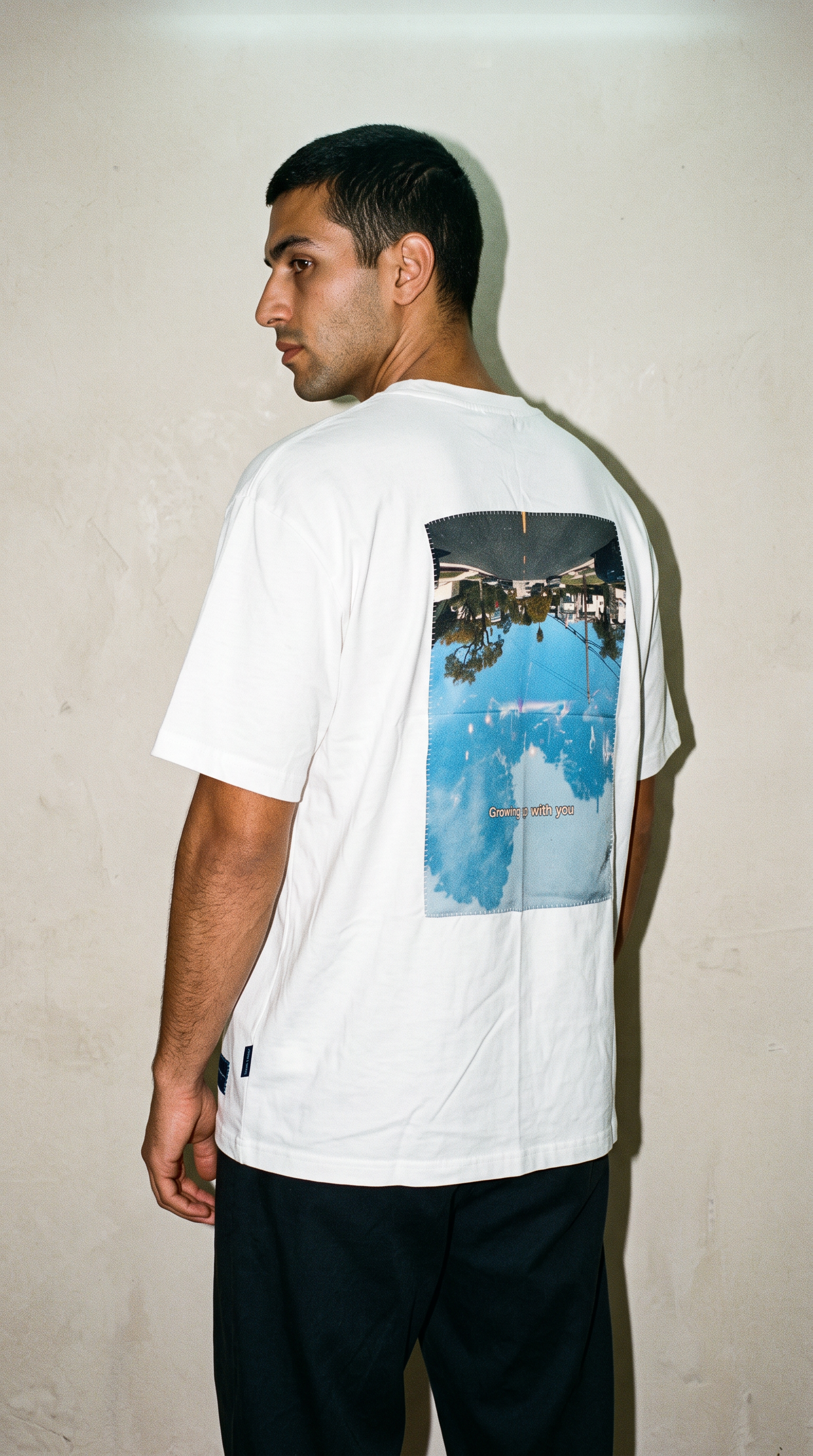 Male model wearing the Granite Island Biancu white T-shirt with a blue-toned fine art photograph printed on silk and hand-stitched onto the back.