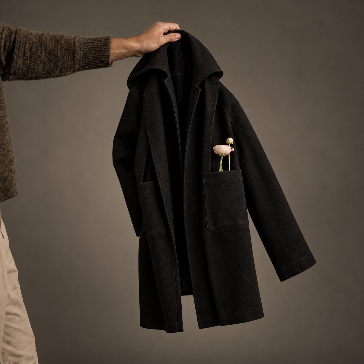 Granite Island black hooded kimono overcoat displayed on a hanger, showing its long relaxed silhouette, front pockets and minimalist construction.