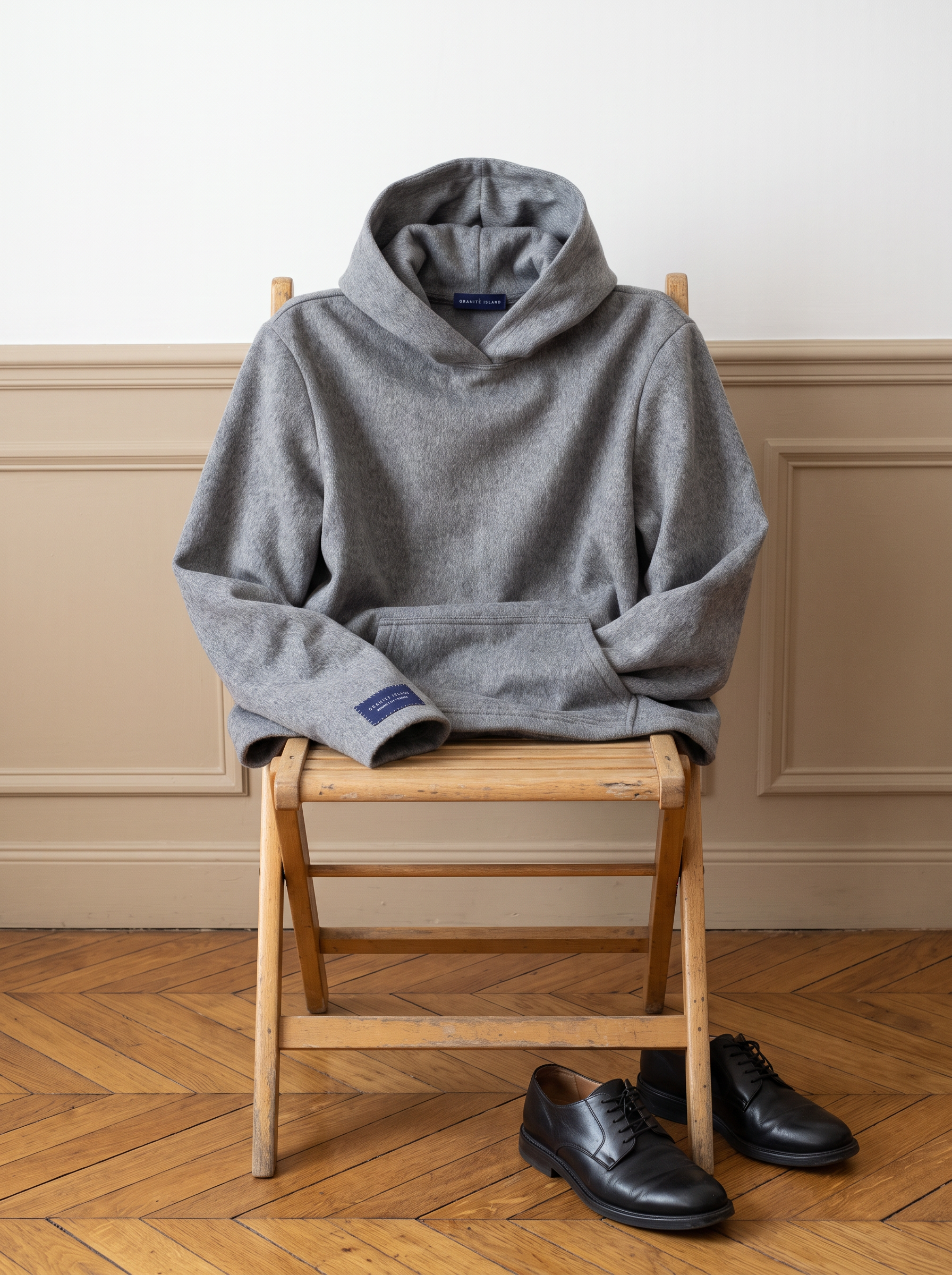 Granite Island Silvery Grey Angora Hoodie displayed on a wooden chair in a minimalist interior, showing its relaxed silhouette and soft grey texture.
