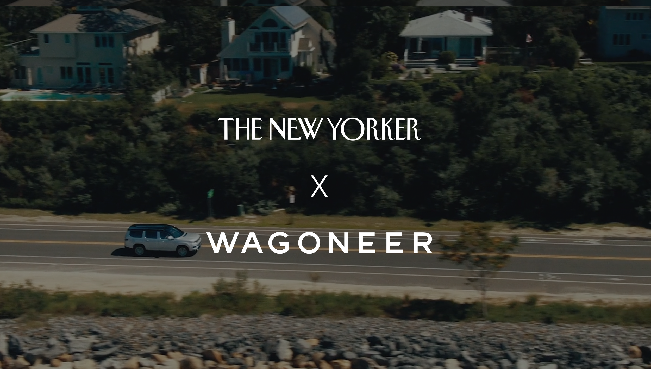 Overhead shot of a silver SUV driving on a road with houses and trees in the background and the text 'The New Yorker x Wagoneer' overlaid on the image.