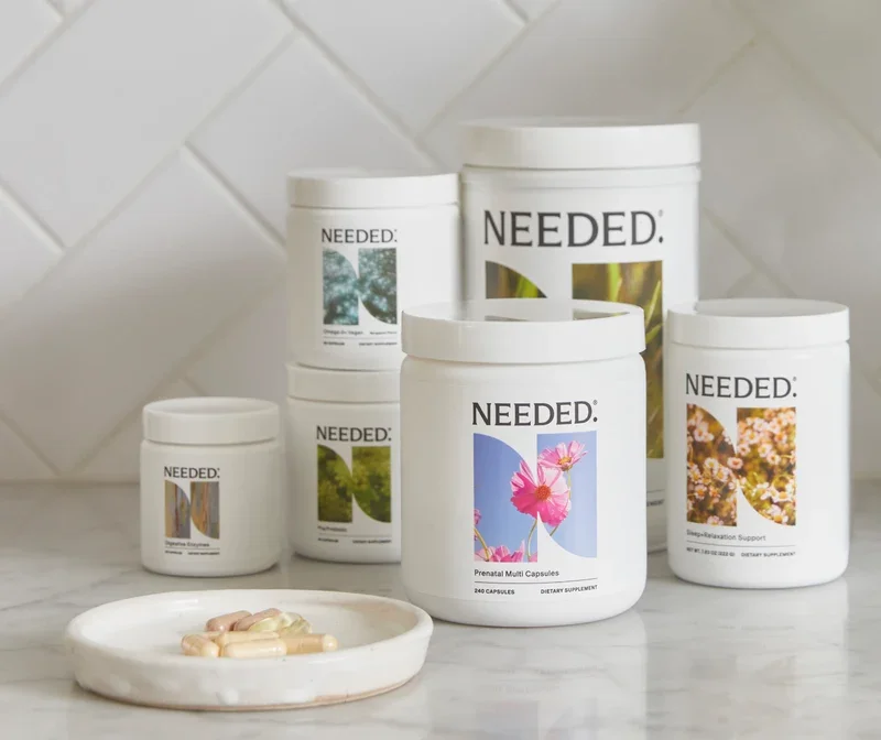 Assorted white supplement containers with labels featuring nature images, placed on a marble surface, with some capsules in a white dish in front.