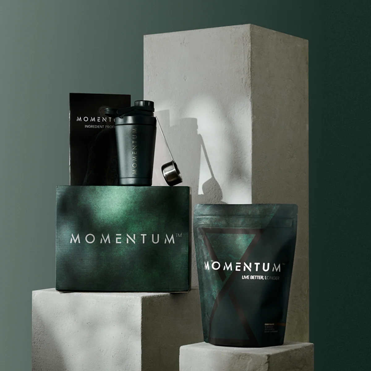 Display of Momentum health and fitness products, including a shaker bottle, a box, and a bag, on a minimalist platform.